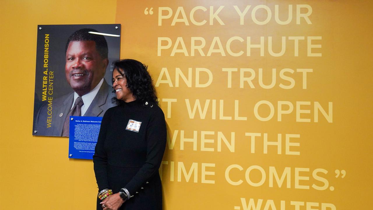 Michele Butler-Robinson stands next to photo of Walter Robinson at Welcome Center.