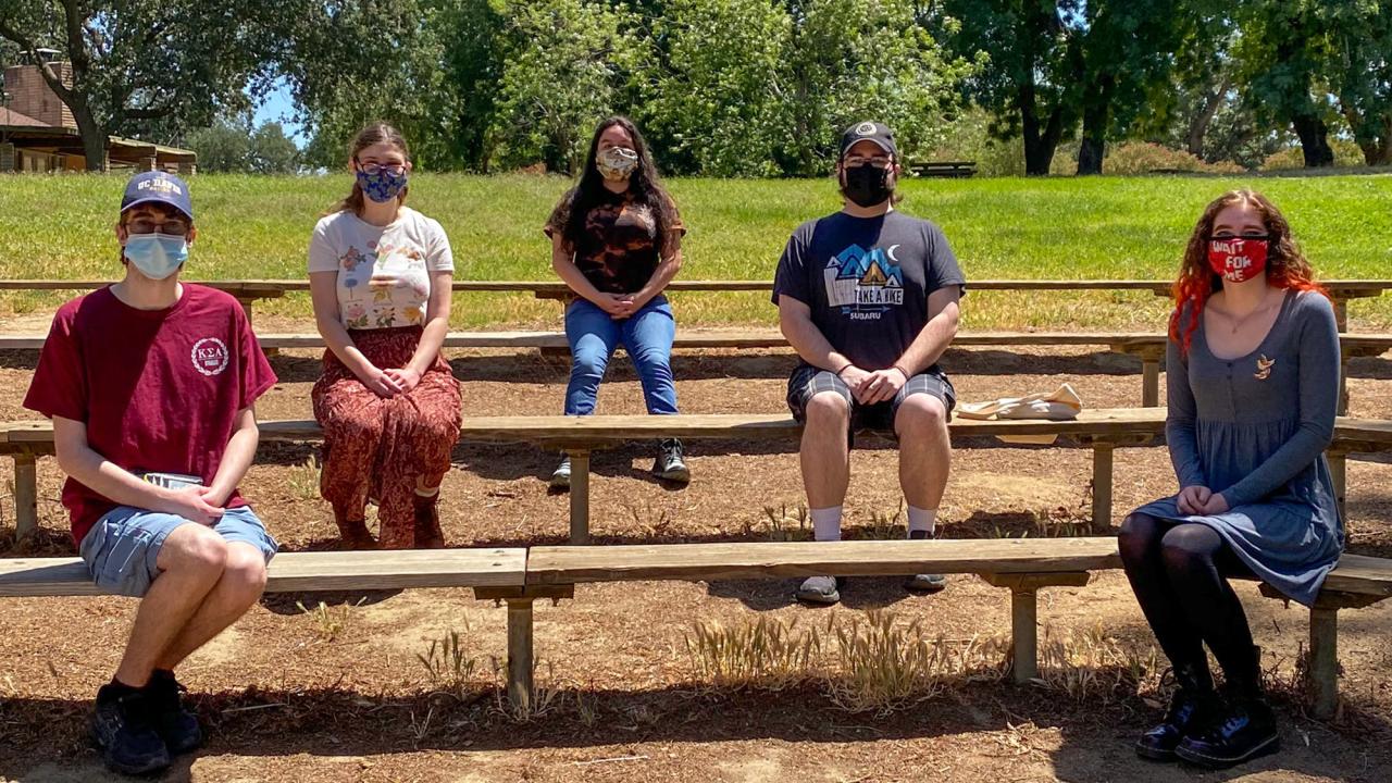 Five students, masked and socially distanced, seated outside.
