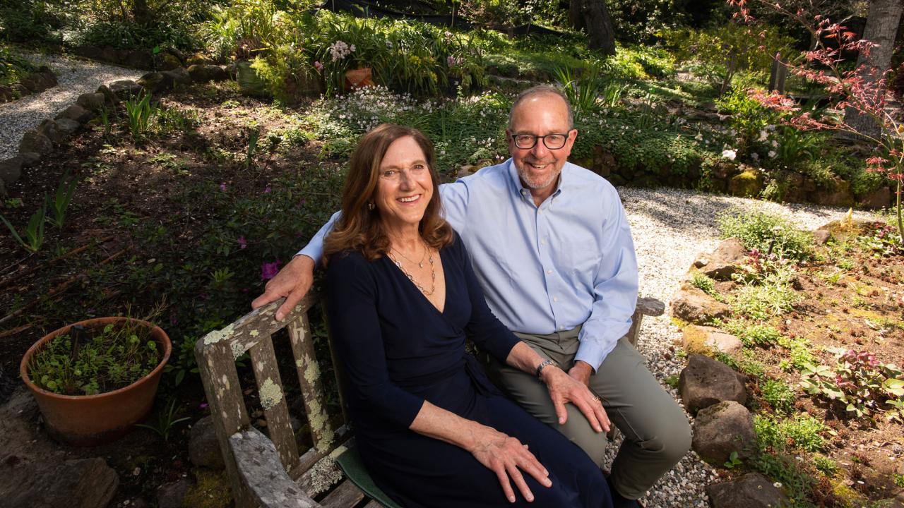 woman and man sitting on bench in park-like setting
