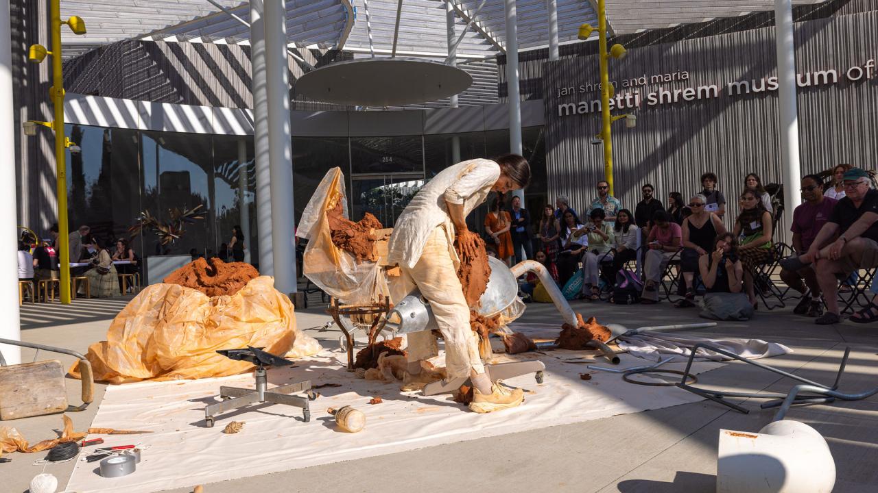 Dancers perform in front of Manetti Shrem Museum, with sign in background