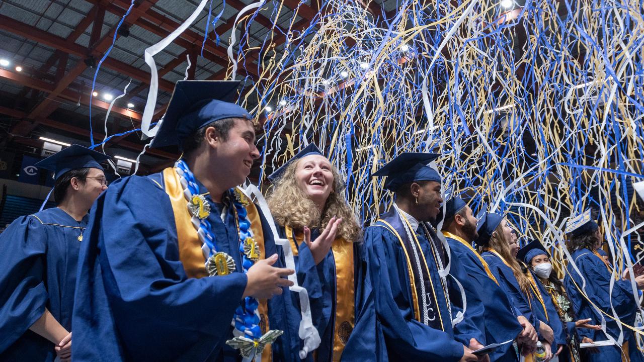 Three graduates beam as streamers fall