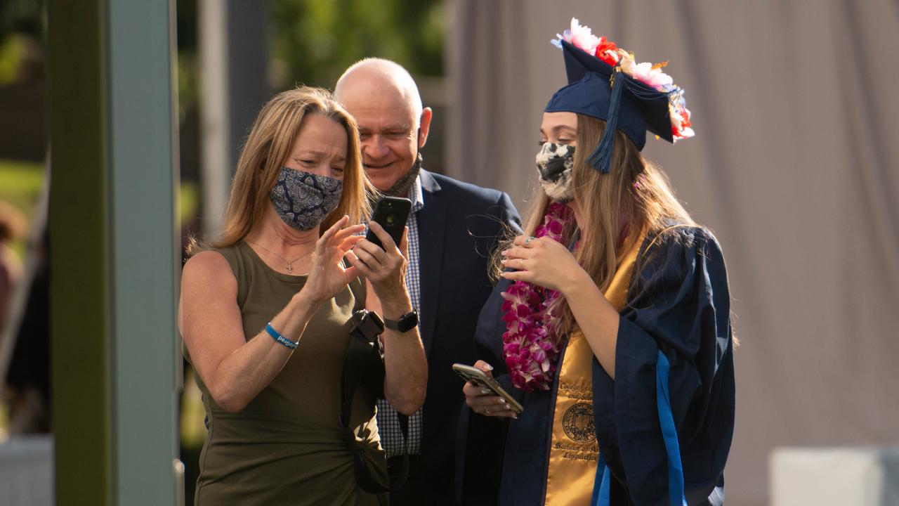 Student talks with parents at commencement.