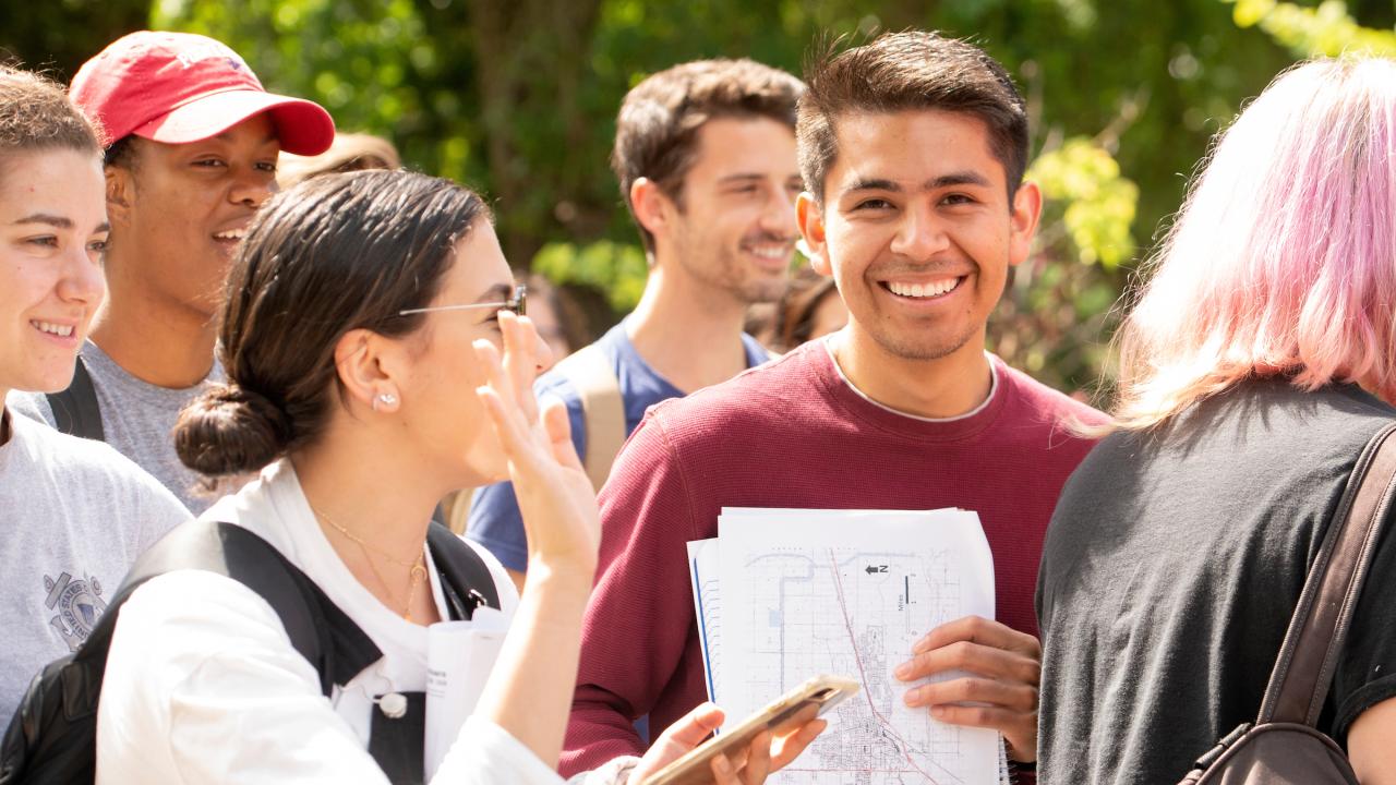 A student smiles outside with his papers at UC Davis. 