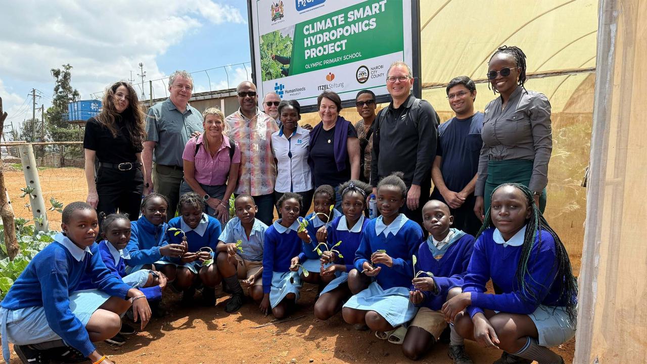 Group of people pose for photo in front of sign that reads "climate smart hydroponics project"
