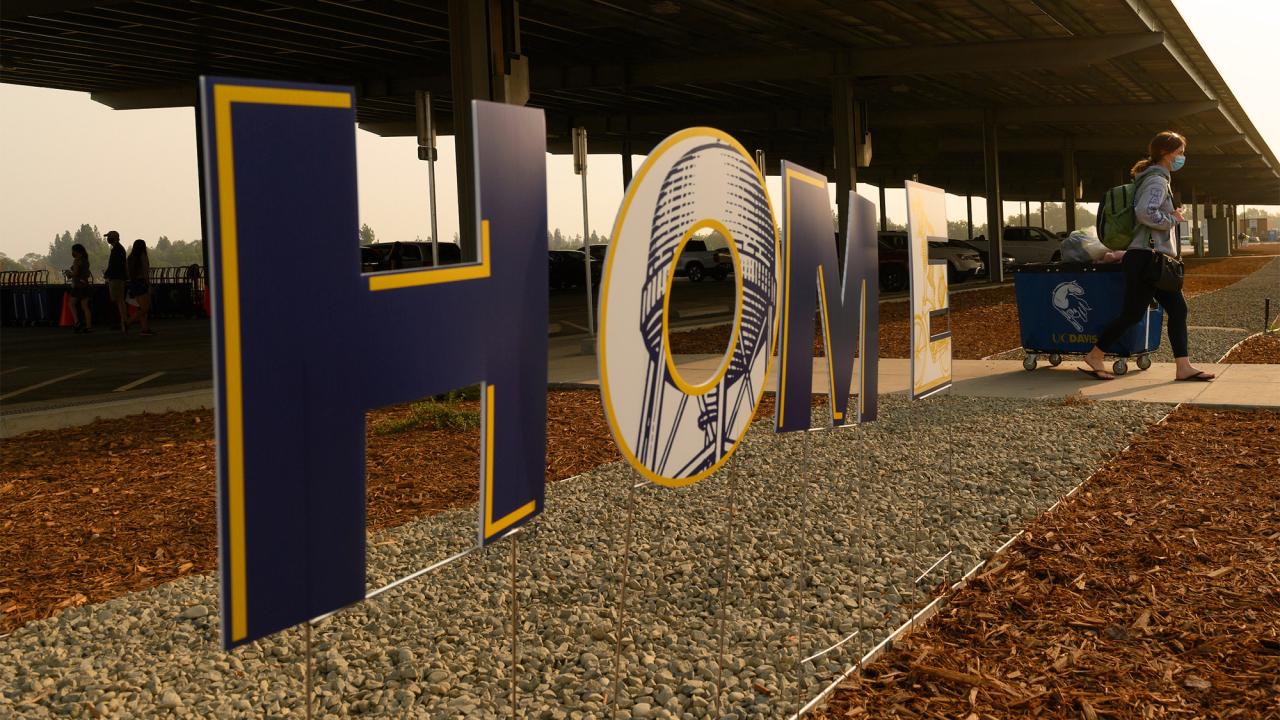 Student walks past large sign reading "HOME"