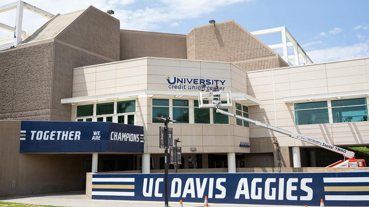 Workers install University Credit Union Center sign at the building’s northeast corner, the main entrance.