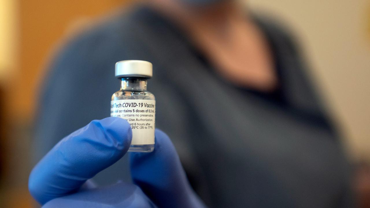 Gloved hand holds empty vial of COVID-19 vaccine.