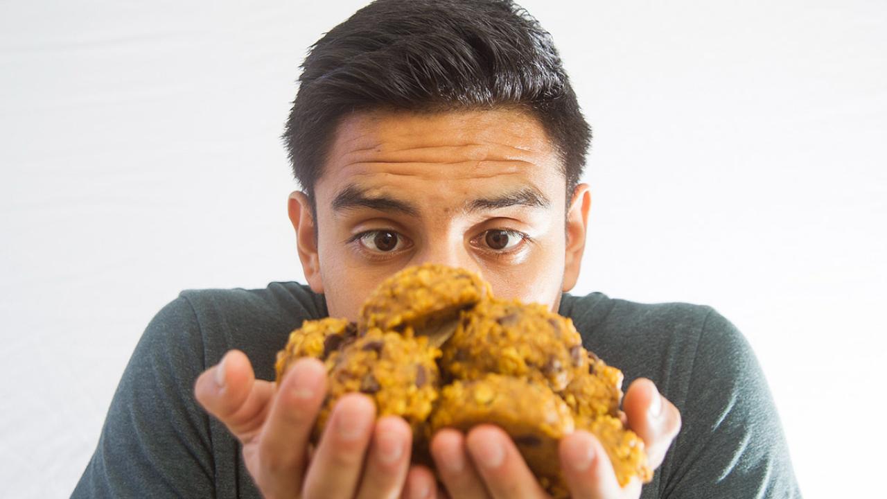 Wide-eyed young man gazes at pile of homemade cookies held in his hands.