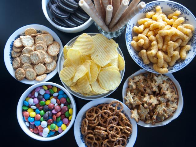 In this episode of Unfold, we uncover the science and debate behind processed and ultra-processed foods. Shown here are seven bowls with various processed and ultra-processed foods, including chips, pretzels and candies.(Getty)