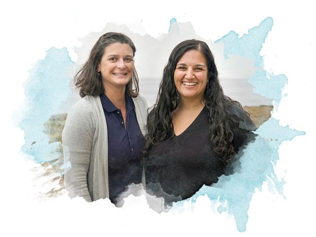 Two women pose in front of the ocean in on the coast of Northern California