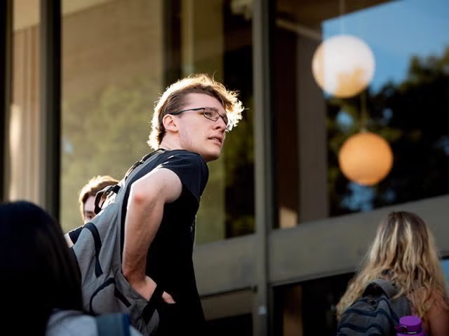 As student in front of a building turning to look at something