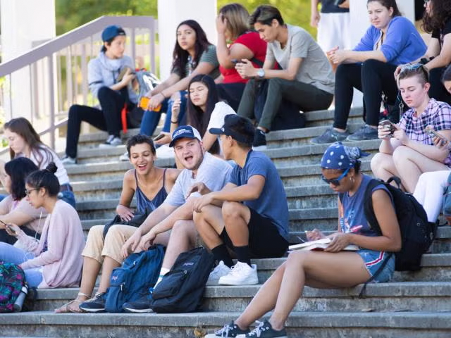 A bunch of students sitting on the steps of a building before class