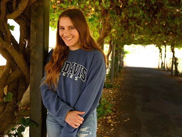 A student posing in front of some trees on campus