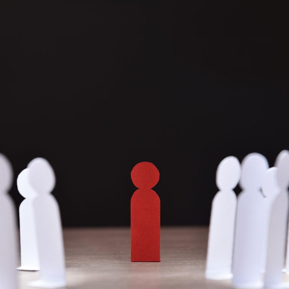 An illustration with one red human icon surrounded by a dozen white human icons