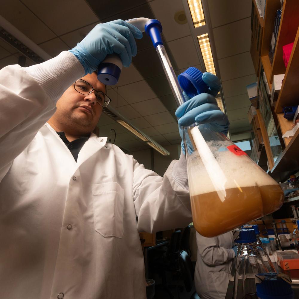 A researcher fills hios flask from a vial in his lab