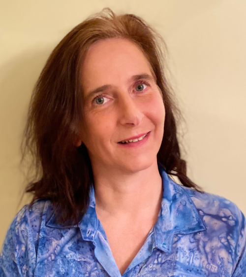 Color head and shoulders of a woman with shoulder-length brown hair. She wears a blue pattern shirt and her head is tilted to the left. 