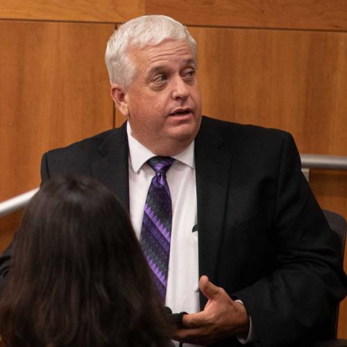 Len Reid-Reynoso, man in suit in front of paneling