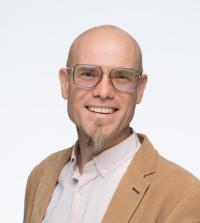 Portrait of a bald man with glasses and a goatee against a white background