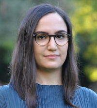 a woman with dark hair and black glasses stares at a angle at the camera for a professional headshot