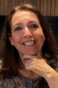 Woman with straight brown hair smiling with hand under her chin