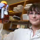 Lynne Hagelthorn holds up a vial in a lab. 