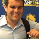 Man leaning on a glass case with sports logos behind him