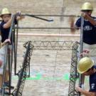 Photo: Four guys in hardhats assembling steel pieces into a bridge