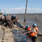 photo: people in hardhats filling sandbags and standing in water