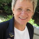 Laurie Lewis displays the centennial lapel pin with the 100-year logo that she designed.