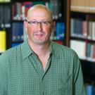 Ari Kelman stands in front of books.
