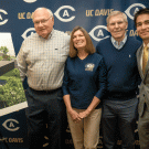 Donors and athletics difrector pose next to rendering of  Student-Athlete Performance Center and practice field,