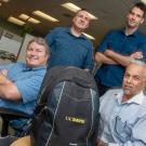 Four men gathered around a backpack