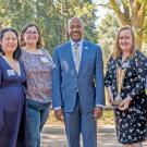 Eight people, posed, in a line, flanked by Lab Safety Award posters.