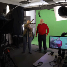 Charlie Bamforth stands in front of green screen.