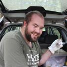 Ben Plourde, seated in back of SUV, holds deer mouse.