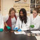 A professor and students look at experiment results at a lab bench.