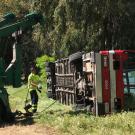 Tow truck tips old Unitrans bus onto its side, for training exercises.