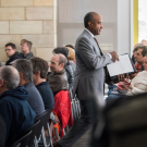 Chancellor May walks in aisle of Academic Senate meeting, holding his remarks.
