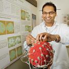 Charan Ranganath, in a lab coat, adjusting wires on a research subject.