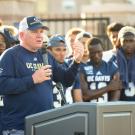 Coach Dan Hawkins at podium, team behind him, at Football Fan Fest