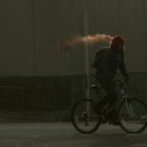 Bicyclist's breath condenses into what looks like a cloud or fog.