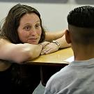 Photo: woman with hands on arms listening to boy with back to camera