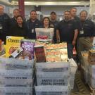 Mail Services crew, lined up behind mail bins full of donated food