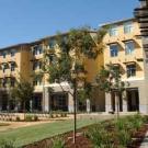 Photo: four-story building with trees and garden in foreground