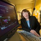 Woman posing near a computer that has images on it