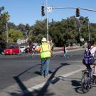 Flagger stops traffic for a bicyclist in crosswalk.