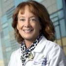 Smiling woman in a doctor's white coat and a leopard skin scarf