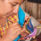Photo: Woman paints decorative bird in "Giving Flight to a Colibri," by Marc Schenker