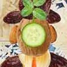 Painting: Maria Robles Gonzalez collage (cropped), showing man with a head of walnut and a cucumber slice in front of his "face"