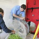 Woman and man working on equipment next to sealed door